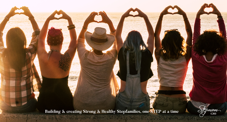 group of women facing the sunset, arms in the air, making heartshapes with the fingers.